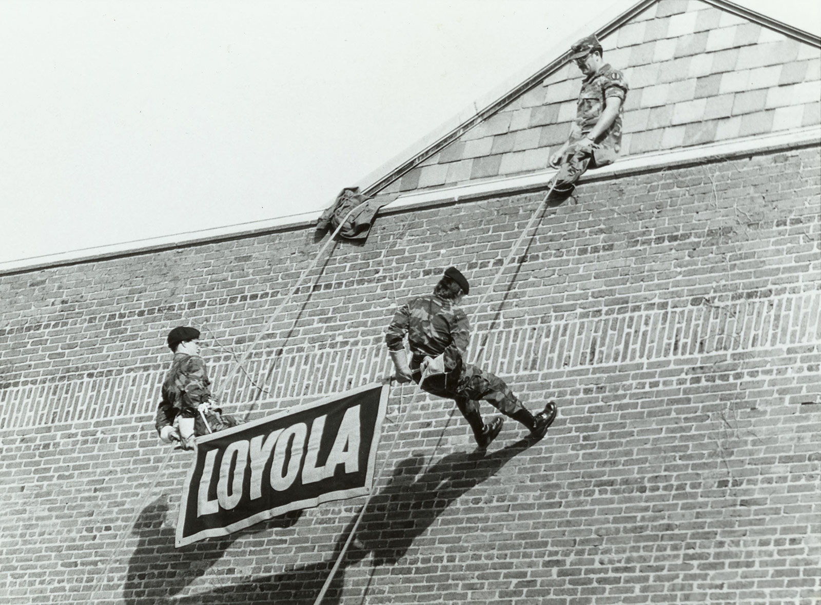ROTC cadets rappelling down the side of the building with a Loyola banner