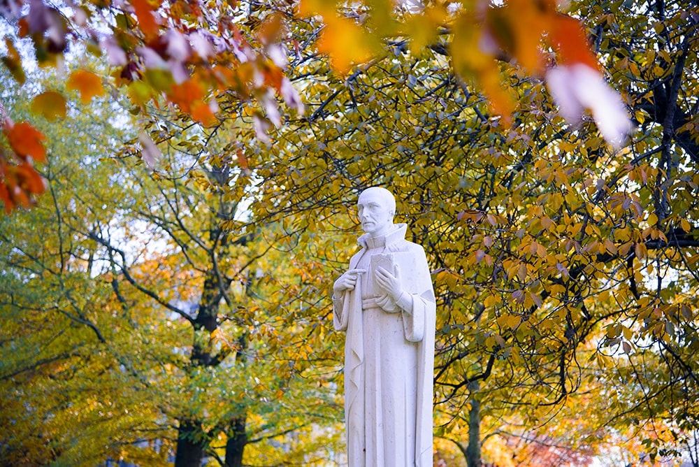 The St. Ignatius statue on the quad framed by fall foliage