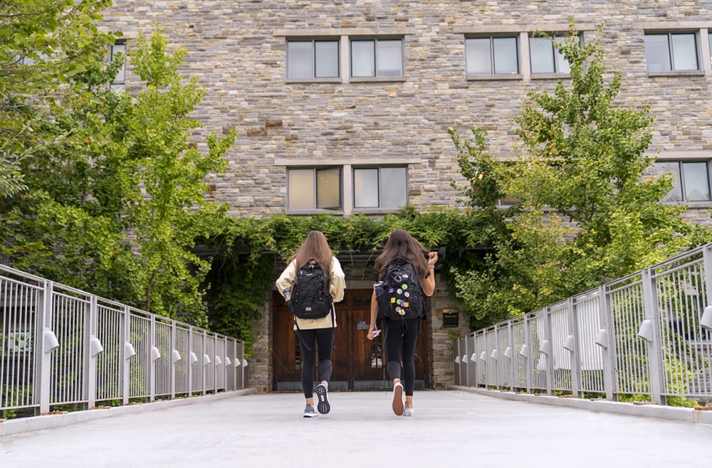 Two students walking on the bridge leading to the front entrance of Maryland Hall