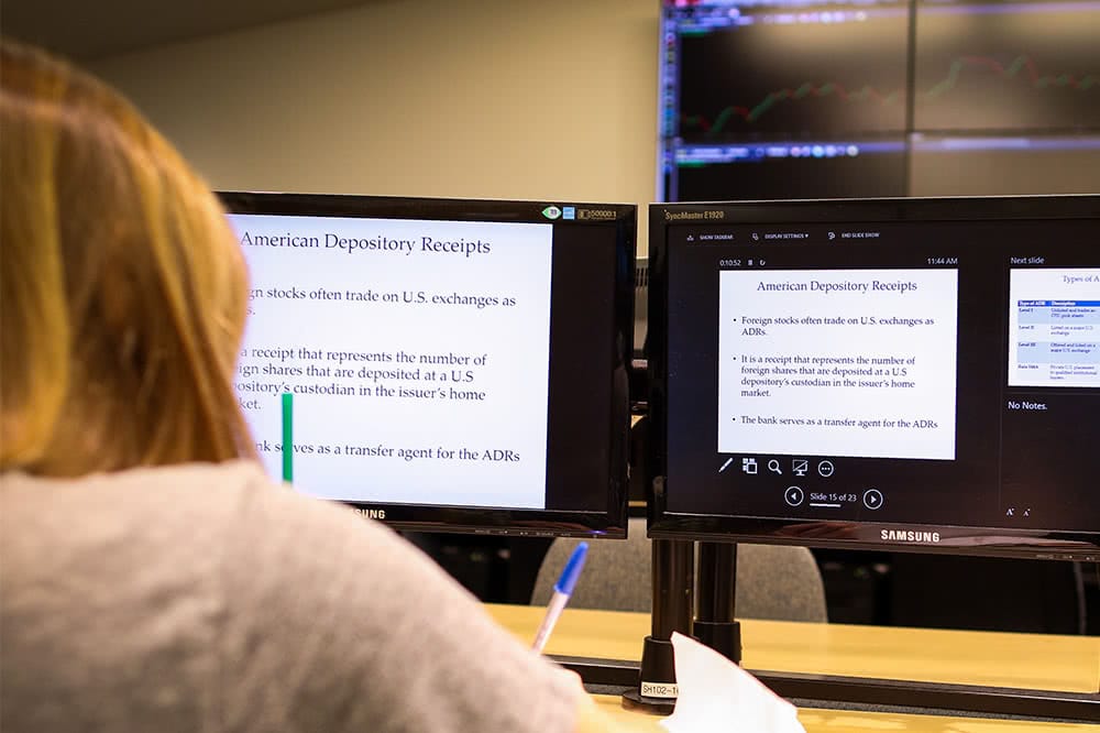 A view from behind of a student sitting in front of a computer screen, which displays information about American depository receipts