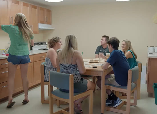 A group of students sitting around a table in a residence hall kitchen