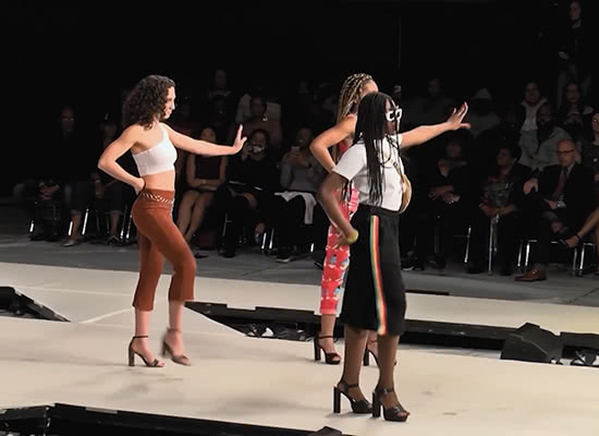 Three female students pose on a catwalk during Loyola's Black Student Association (BSA) Fashion Show