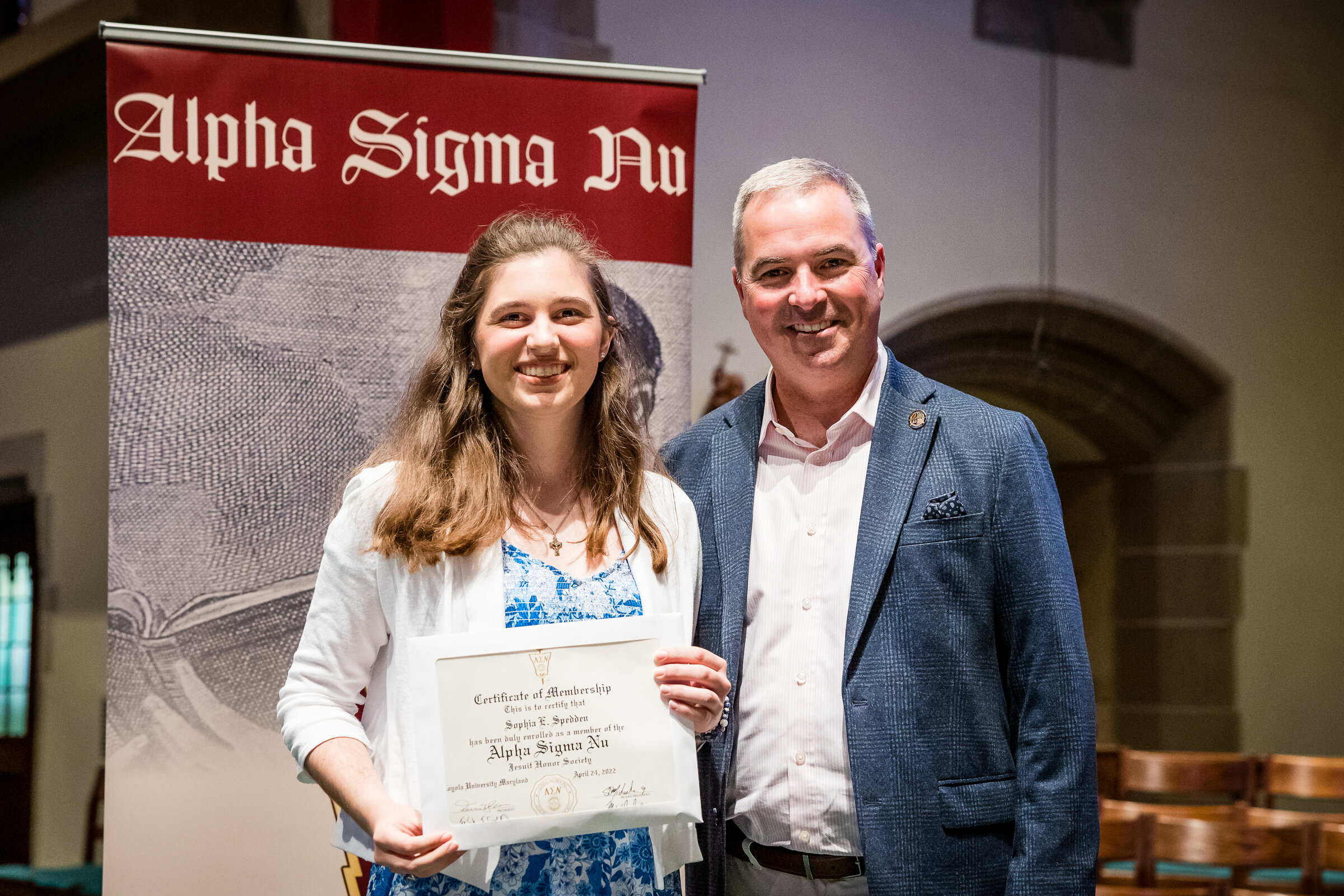 Loyola's President standing next to an Alpha Sigma Nu member holding their certificate
