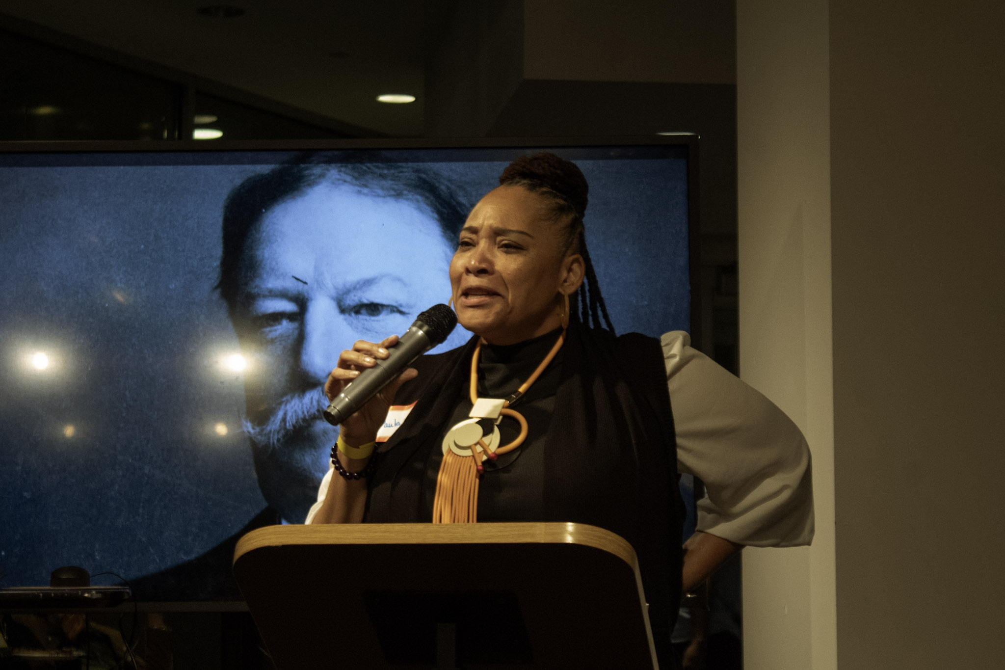 A poet stands at a podium, speaking an emotional spoken word piece