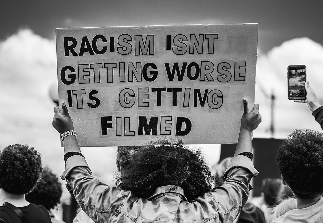 A protestor holding a sign that reads: Racism isn't getting worse, it's getting filmed