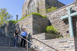 Student and Professor walk and talk next to Loyola chapel
