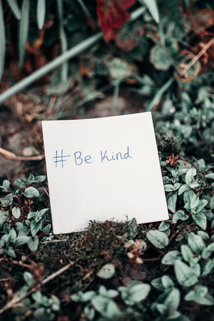 sticky note with #BeKind on the ground with leaves