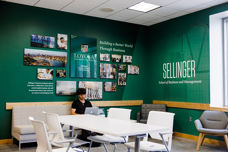 A student sits inside Loyola's Sellinger School of Business and Management and studies on their laptop.