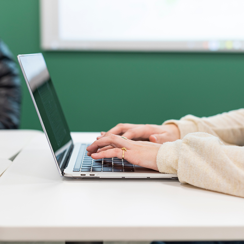 Student typing on laptop.