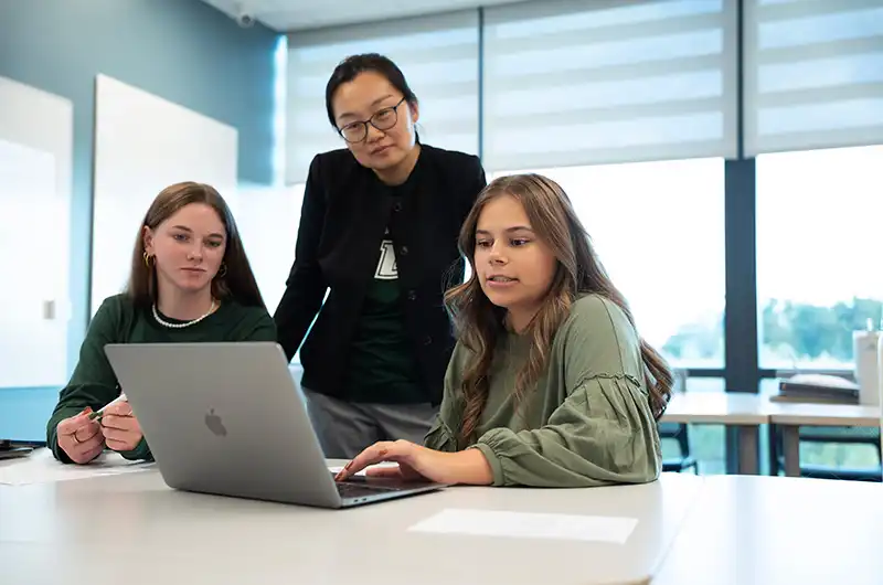 A Loyola University Maryland professor works with two students