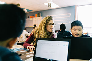 Teacher and Hispanic student working on laptop
