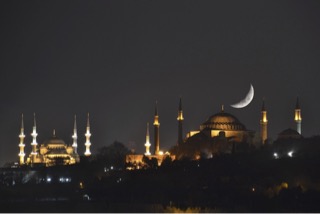 night skyline of Turkey with a crescent moon above a dome-shpaed building