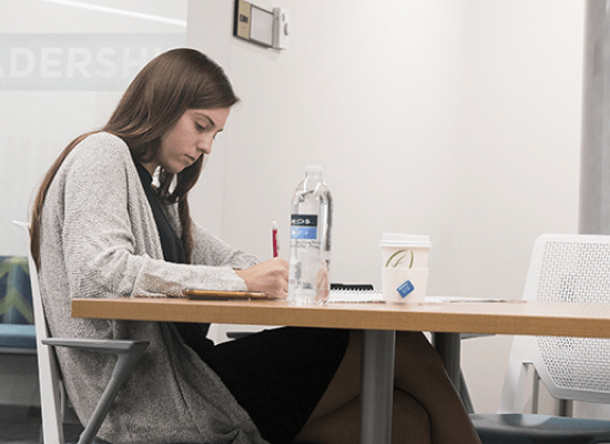 a student seated at the desk looking focused and taking notes