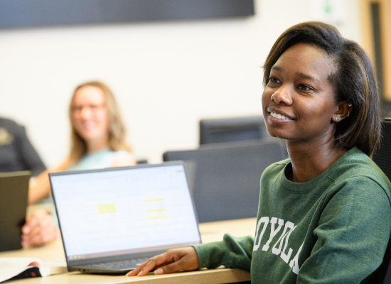 a student seated at their desk while smiling and paying attention during class