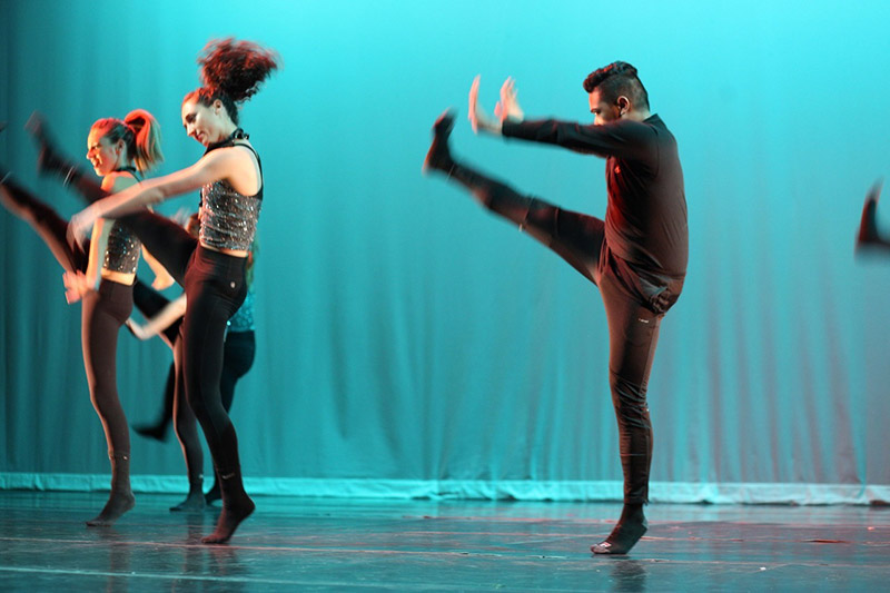 Students kicking their legs up during a dance performance