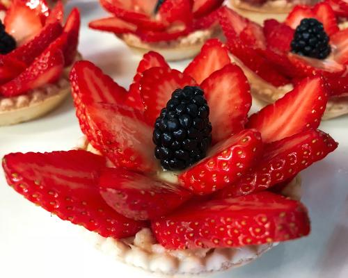 Sliced strawberries and a blackberry artfully arranged on a mini cheesecake