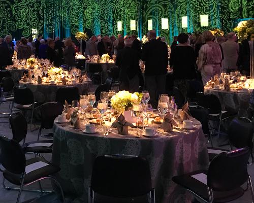 Round tables beautifully prepared for an elegant reception, with attendees milling in the background