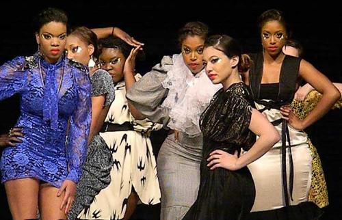 7 female models on stage in differing outfits and poses.