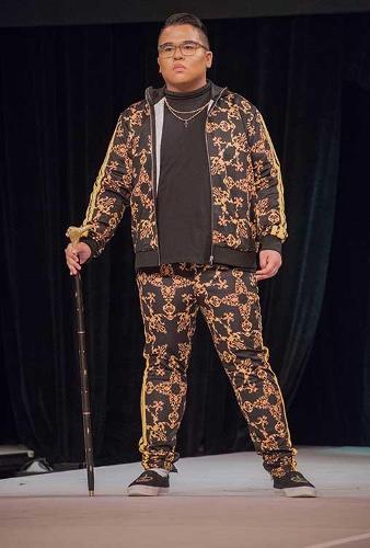 Male model posing on the catwalk with a cane and bold printed sweat suit.