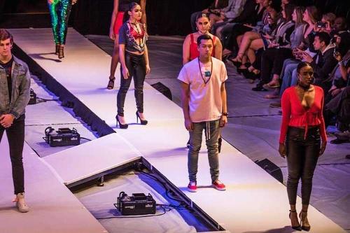 Female and male models standing in simple poses on the runway, wearing a white, black, and red color scheme.