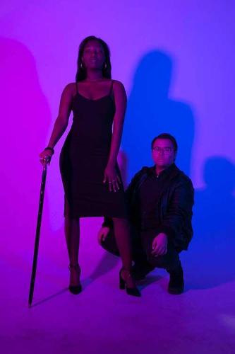 A female and male student model posing under an intense purple and blue hue.