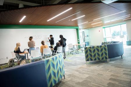 Students of color gather around a whiteboard to study in the Center for Intercultural Engagement (CIE)